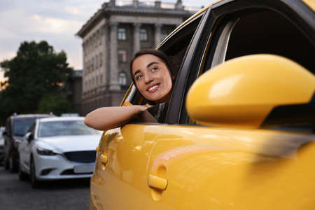 Beautiful young woman looking out of taxi window outdoorsの写真素材