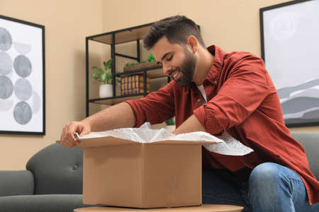 Man unpacking parcel at home. Online shoppingの写真素材
