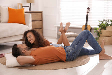 Lovely couple enjoying each other on floor in living roomの写真素材