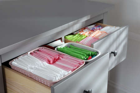 Open cabinet drawers with menstrual pads, tampons and pantyliners indoors, closeupの写真素材