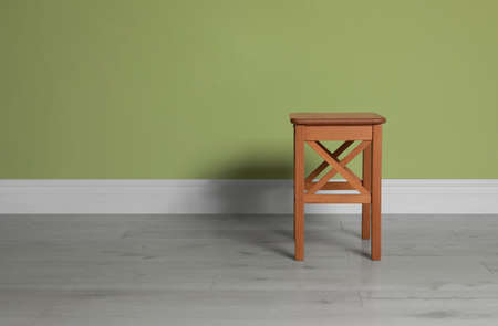 Stylish wooden stool near light green wall indoors. Space for textの写真素材