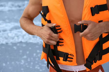 Lifeguard putting on life vest near sea, closeupの写真素材