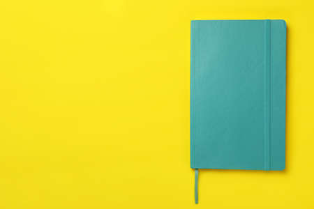 New stylish planner with hard cover on yellow background, top view. Space for textの写真素材