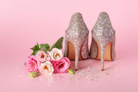 Stylish women's high heeled shoes and beautiful flowers on pink backgroundの写真素材
