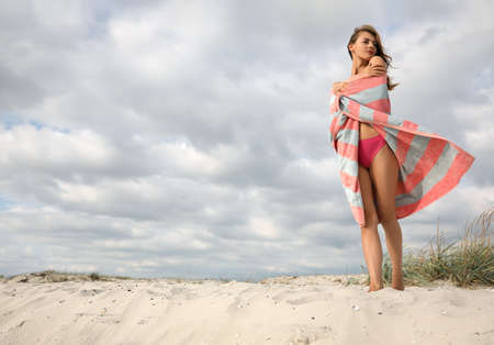 Beautiful woman with beach towel on sandの写真素材