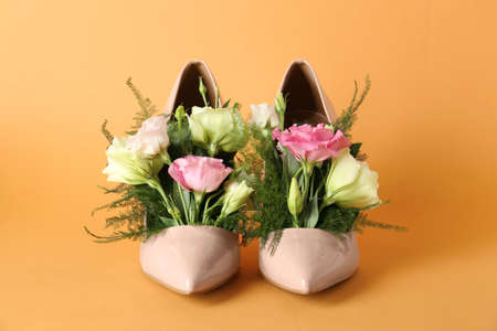 Stylish women's high heeled shoes with beautiful flowers on pale orange backgroundの写真素材