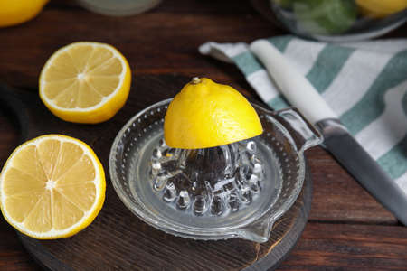 Glass squeezer and fresh lemons on wooden tableの写真素材