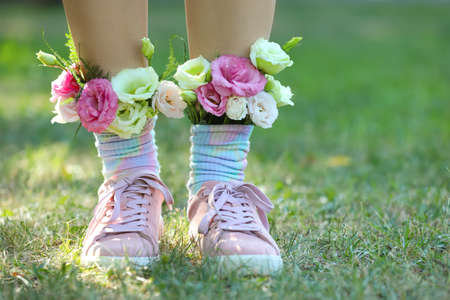 Woman standing on green grass with flowers in socks, closeup. Space for textの写真素材