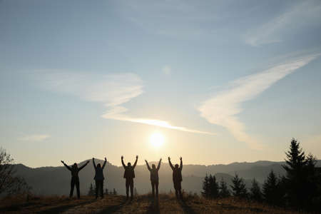 Group of people enjoying sunrise in mountains, back view. Space for textの写真素材