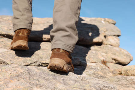 Tourist climbing on cliff, closeup of legsの写真素材