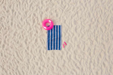 Striped beach towel, flip flops and swim ring on sand, aerial viewの写真素材