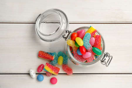 Jar with different delicious candies on white wooden table, flat layの写真素材