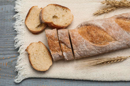 Cut delicious French baguette on gray wooden table, top viewの写真素材