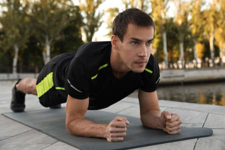 Sporty man doing plank exercise on mat outdoorsの写真素材