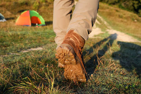 Tourist walking on green grass, closeup of legs