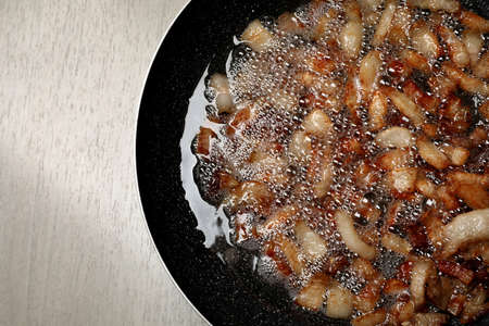Tasty cooked cracklings in frying pan on light wooden table, top view. Pork lardの写真素材