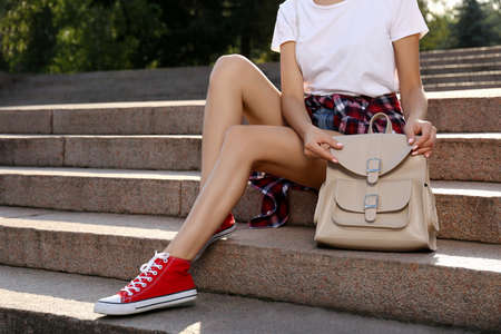 Young woman with stylish beige backpack on stairs outdoors, closeupの写真素材