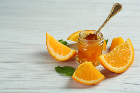 Jar of sweet orange jam and mint on white wooden table, space for textの写真素材
