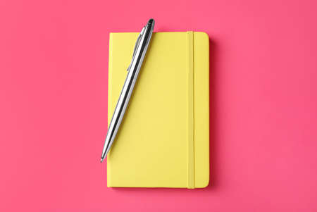 New stylish planner with hard cover and pen on pink background, top viewの写真素材