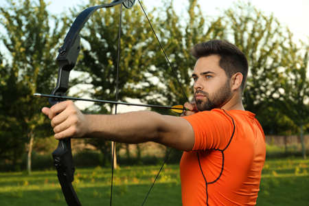 Man with bow and arrow practicing archery in parkの写真素材