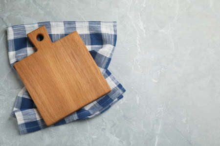 Kitchen towel and wooden cutting board on gray table, top view. Space for textの写真素材