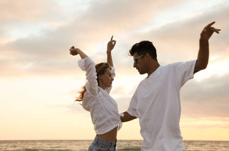 Happy couple dancing on beach at sunsetの写真素材
