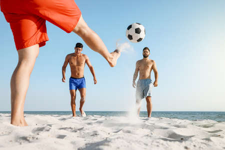 Group of friends playing football on beachの写真素材
