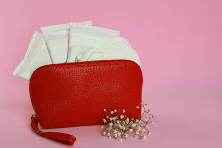 Menstrual pads, pantyliners and tampons in bag near flowers on pink backgroundの写真素材