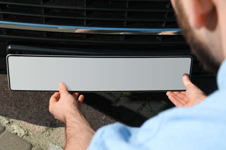 Man installing vehicle registration plate outdoors, closeupの写真素材