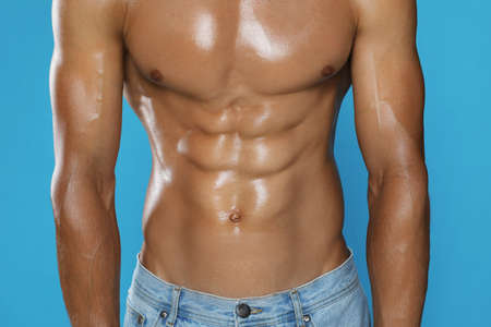 Shirtless man with slim body on light blue background, closeup