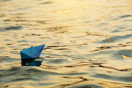 Paper boat floating on water outdoors. Space for textの写真素材
