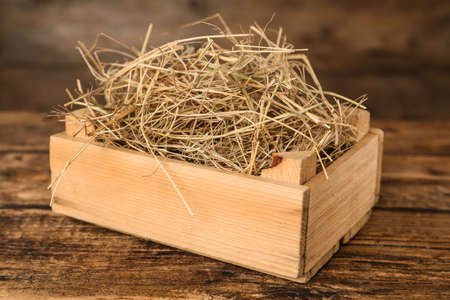Dried hay in crate on wooden tableの写真素材
