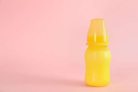 Feeding bottle with infant formula on pink background, space for text. Baby milkの写真素材