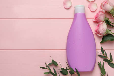 Bottle of shower gel, roses and green leaves on pink wooden background, flat lay. Space for textの写真素材