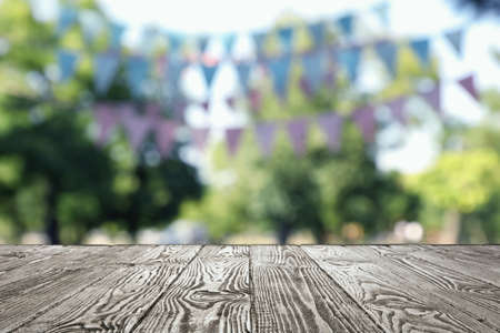Empty black wooden table in park decorated with bunting flags, space for design. Outdoor partyの写真素材