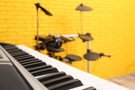 Musical instruments near yellow wall indoors, focus on synthesizer. Band practiceの写真素材