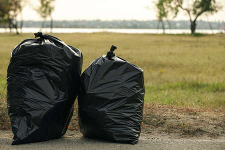 Trash bags full of garbage on pavement outdoorsの写真素材