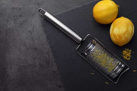 Grater and fresh lemons on black table, flat lay. Space for textの写真素材