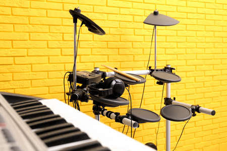 Electronic drum kit and synthesizer near yellow brick wall indoors. Musical band practiceの写真素材