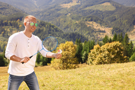 Man playing badminton in mountains on sunny day. Space for textの写真素材