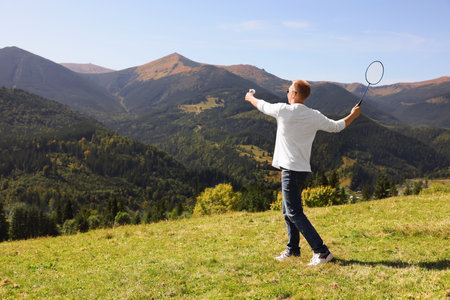 Man playing badminton in mountains on sunny day. Space for textの写真素材