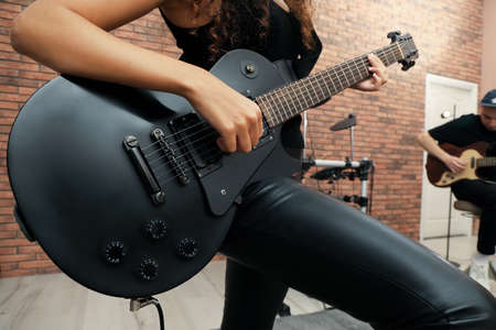 African American woman playing electric guitar during rehearsal in studio, closeup. Music band practiceの写真素材