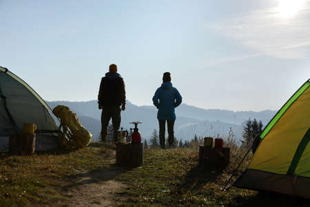 Couple enjoying beautiful mountain landscape near camping tents, back viewの写真素材