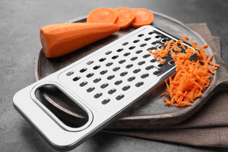 Grater and fresh ripe carrot on grey table, closeupの写真素材