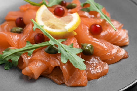 Salmon carpaccio with capers, cranberries, arugula and lemon on plate, closeupの写真素材