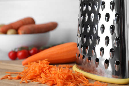 Grater and fresh ripe carrot on wooden board, closeupの写真素材