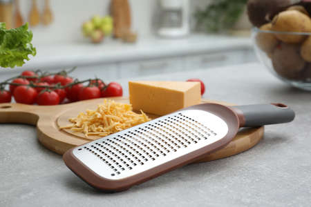 Grater and cheese on grey table in kitchenの写真素材
