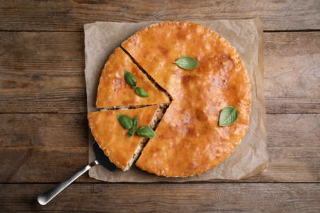 Delicious pie with meat and basil on wooden table, top viewの写真素材