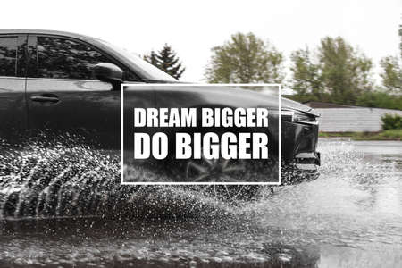 Dream Bigger Do Bigger. Inspirational quote motivating to set life goals freely and forget about reasons that can hold back. Text against luxury car outdoorsの写真素材