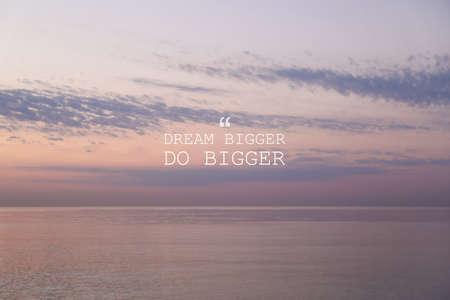 Dream Bigger Do Bigger. Inspirational quote motivating to set life goals freely and forget about reasons that can hold back. Text against seascape in morningの写真素材